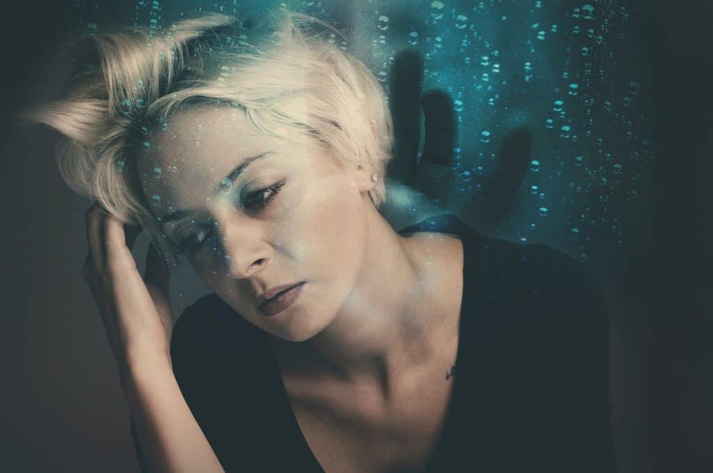 Woman with eyes closed looking haunted, trauma and PTSD therapy in Ontario